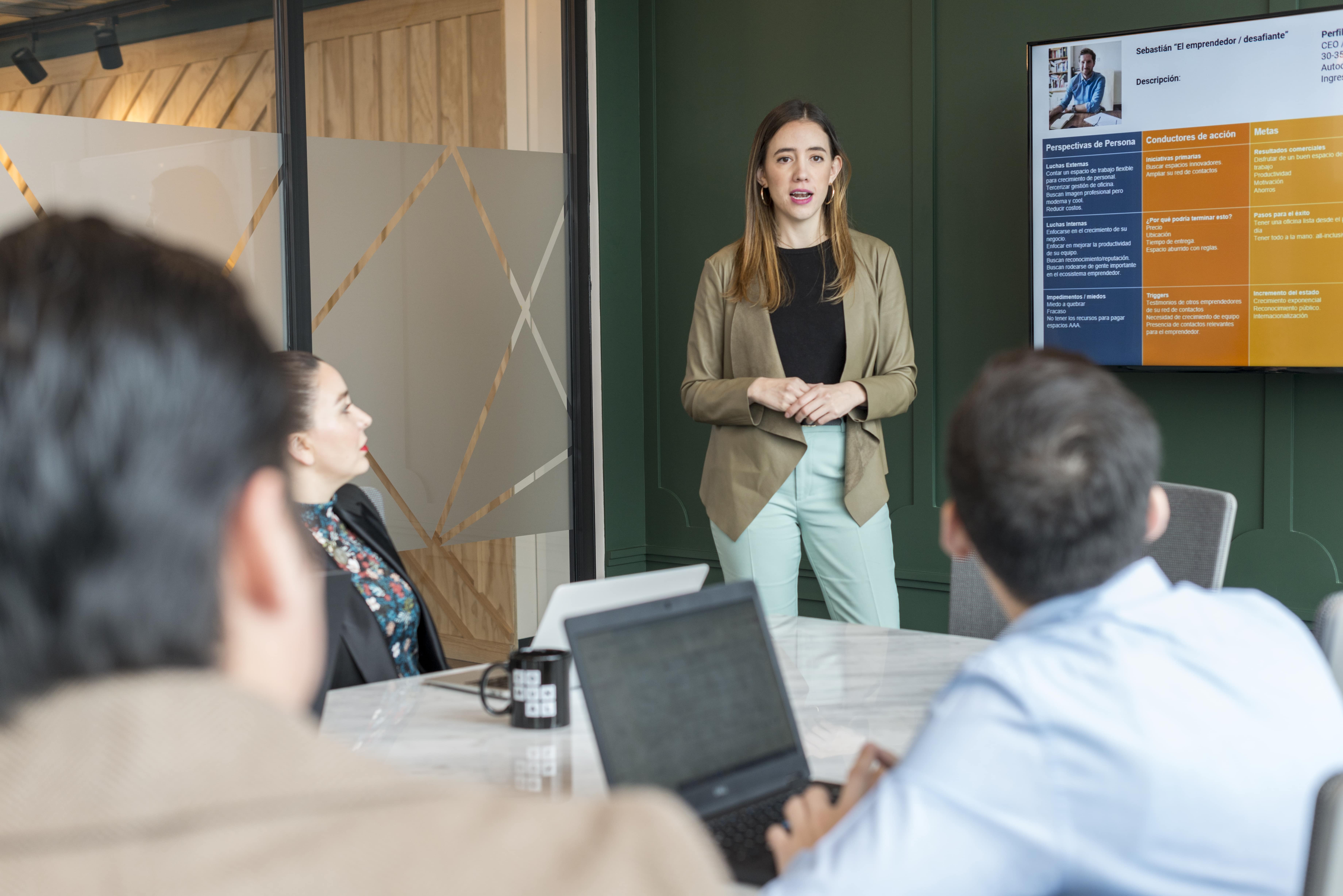 mujer exponiendo en una reunion frente a su equipo