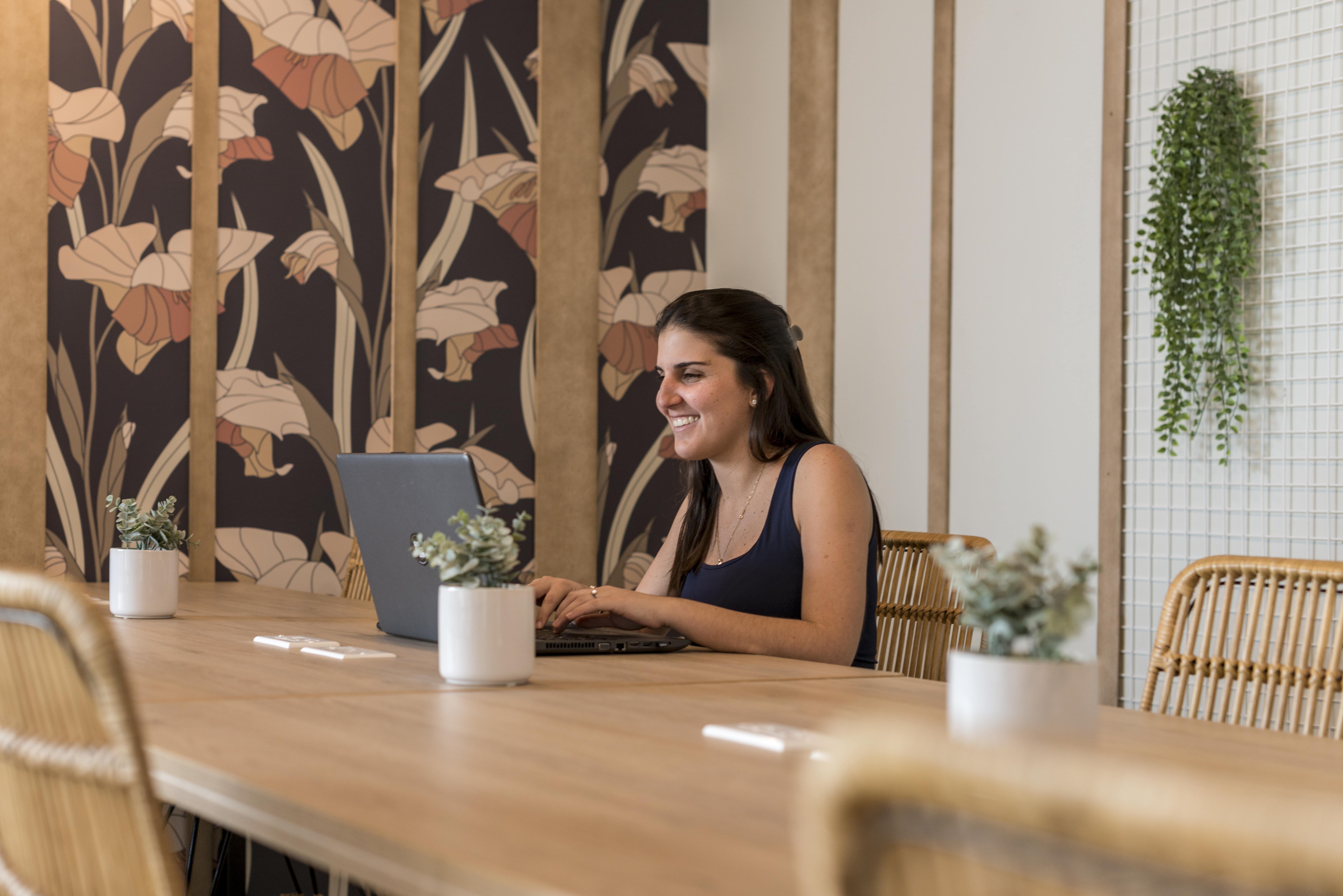 mujer joven trabajando alegremente en su laptop desde casa